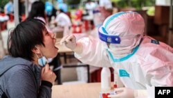 中国医护人员在沈阳新冠病毒检测中心为一名妇女做核酸检测。(2021年5月20日)