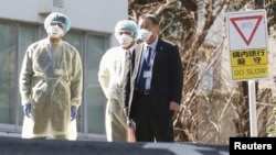 日本卫生官员戴着防疫口罩在东京的国立国际医疗研究中心等候从武汉撤回国的日本侨民。(2020年1月30日)