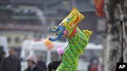 1月23号农历年初一,一名男子抱着龙形气球坐在上海龙华庙门口
