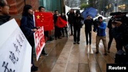 在加拿大不列颠哥伦比亚省一家正在审理孟晚舟案的法院外手举中国国旗和标语牌的孟晚舟支持者。(2018年12月11日)