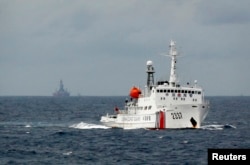 南中国海上的一艘中国海警船,不远处是中国的海上钻井平台。(2014年6月资料照)