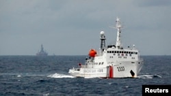 南中国海上的一艘中国海警船,不远处是中国的海上钻井平台。(2014年6月资料照)