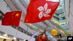 资料图: 一些香港亲政府人士在观看体育赛事时手举中国和香港旗帜。(美联社2021年7月30日)