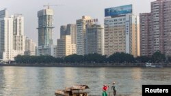 资料照:2013年12月7日,广东省广州市,一对夫妇沿着珠江(或珠江)附近的办公楼钓鱼。(路透社)