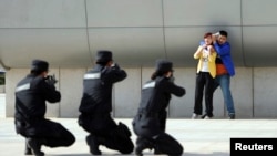 2014年五月7日,中国郑州警方在火车站举行反恐演习。武装警察举枪瞄准一个劫持妇女的恐怖分子的扮演者