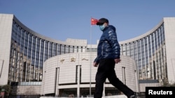 一名戴着口罩的男子走过北京的中国人民银行总部。(2020年2月3日)