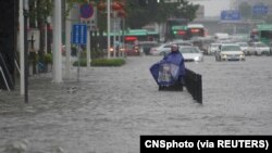 中国河南省郑州市一名市民站在洪水泛滥的街道上。(2021年7月20日)