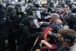 身着防暴装备的国会警察在1月6日的骚乱中,将一些试图冲入国会大厦的抗议者推回去。