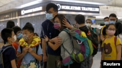 资料照片:香港一名妇女在香港机场前往英国前与家人分别(2021年6月30日)