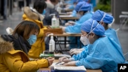 北京一位女子正在医务人员的指导下填写个人信息准备接种新冠病毒疫苗。(2021年1月15日)