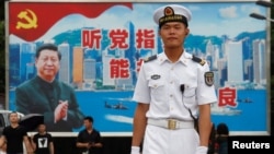在香港海军基地,一位中国水兵站在一面具有中共党旗、习近平像和香港景象的大型看板前面(2017年7月8日)。