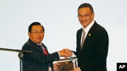 现任轮值主席国马来西亚的防长希山慕丁·侯赛因(Hishamuddin Hussein,右)向老挝国防部部长任桑努·沙雅拉(Sengnouane Sayalat)做了东盟轮值主席国转交。