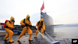 中国海军发布的照片显示,在青岛潜艇基地穿着防护服的水兵清洁核潜艇 (2013年10月)