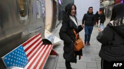 中国购物者在北京一个热门购物中心,长凳上画着美国国旗。(2019年1月6日)