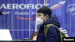 资料照:一名戴着口罩的旅客在俄罗斯谢列梅捷沃国际机场的俄罗斯航空公司订票柜台旁。(2020年2月4日)