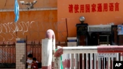 新疆喀什地区伽师县一所小学校门有铁丝网和监控镜头,校门前写着:请使用国家通用语言。(2018年8月31日)