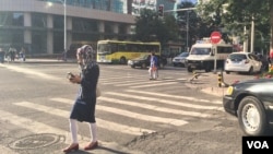 乌鲁木齐街头有妇女边走边看手机(2015年3月,VOA图片)