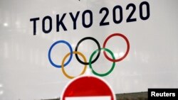 东京街头交通警示牌后的东京奥运会旗帜。(2020年3月23日)