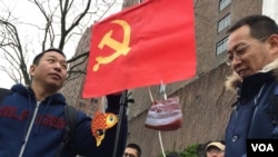 在纽约联合国大楼前的抗议者。中共党旗下面挂着象征腐败的鱼肉图片(2017年2月7日,美国之音章真拍摄)