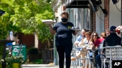 一名餐馆服务员在北卡罗来纳州教堂山的地中海熟食店的人行道上用餐的顾客上菜。上个季度,美国经济以6.4%的年增长率快速增长。