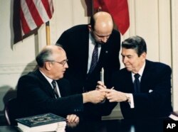 1987年12月8日美国总统里根(右)与苏联领导人戈尔巴乔夫签署《中导条约》后交换签字笔