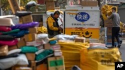 2021年11月16,一家私人快递公司的工人在北京一栋住宅公寓楼附近的一个取件点整理堆积的包裹。(美联社照片)