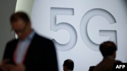 在巴塞罗那举行的世界移动通信大会(MWC)上,人们走过5G展台。(2018年2月26日)