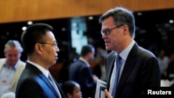 美国驻WTO大使丹尼斯·谢伊(Dennis Shea,又译习达难) (右)在瑞士日内瓦举行的世界贸易组织会议上与中国驻WTO大使张向晨交谈。(2018年7月26日)
