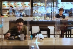 台北餐馆在新冠疫情期间采取措施,吃午餐的顾客之间隔着塑料屏并保持距离。(2021年5月12日)