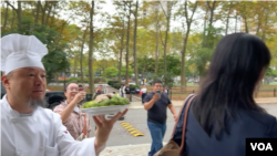 在纽约曼哈顿联邦法院外,抗议人士何岸泉向被控非法充当中国政府代理人的孙雯端上一盘盐水鸭。(2024年9月25日)