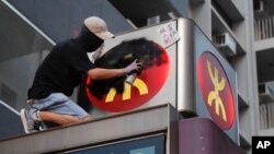 一名香港抗议者在港铁太子站外向港铁标志喷涂黑色燃料。(2019年9月6日)