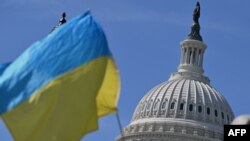 乌克兰支持者2024年4月23日在美国国会大楼外摇旗敦促国会通过950亿美元外援方案。(法新社)