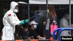 一名台湾士兵向一名离开台北新冠病毒检测中心的女子身上喷洒消毒药水。(2021年5月18日)