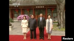 中国国家主席习近平和夫人彭丽媛在北京钓鱼台国宾馆的养源斋前面同朝鲜国务委员会委员长金正恩和夫人李雪主合影。他们在养源斋共进午餐(2018年3月28日发布的视频的截图)。