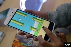 河内一家智能手机店的雇员在玩Flappy Bird(像素鸟)游戏。