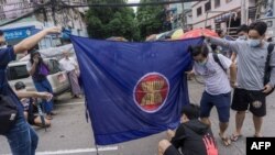 资料照:2021年6月14日,在仰光参加反对军事政变快闪示威的抗议者准备焚烧东盟旗帜(法新社)。