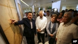 2014年9月11日,在菲律宾举办的有关南中国海岛屿主权历史问题展览上,菲律宾外交部长罗萨里奥(左二)、司法部长德利马(右二)和国防部长加斯明(右)在一幅古地图前听取最高法院大法官卡皮奥的解说。