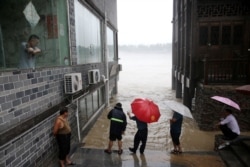 中国重庆市黔江区暴雨过后,人们观察到遭受洪水袭击的卓水古镇河流的水位上升。(2020年6月28日)
