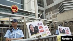 示威者在香港中联办大楼外面放置了要求释放高瑜的标语和图片,旁边是警察(2015年4月17日)