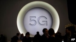 在巴塞罗那举行的世界移动通信大会(MWC)上人们站在5G展台旁。(2018年2月28日)