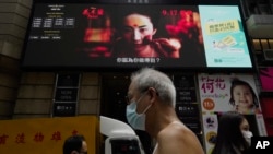 资料照:人们走过在香港市中心街道旁巨大电子屏幕上播放的电影“花木兰”的海报。( 2020 年 9 月 17 日)