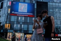 北京市民在观看街头电子屏幕上官媒央视播放的中国军队在台湾附近举行实弹军演的报道。(2022年8月3日)