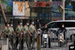 在美国驻北京大使馆外守卫的保安看一队武警走过。(2022年8月3日)