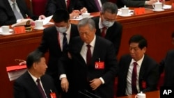 2022 年 10 月 22 日,在北京人民大会堂举行的中国执政的共产党第 20 次全国代表大会闭幕式上,中国前国家主席胡锦涛(中)被护送离开。