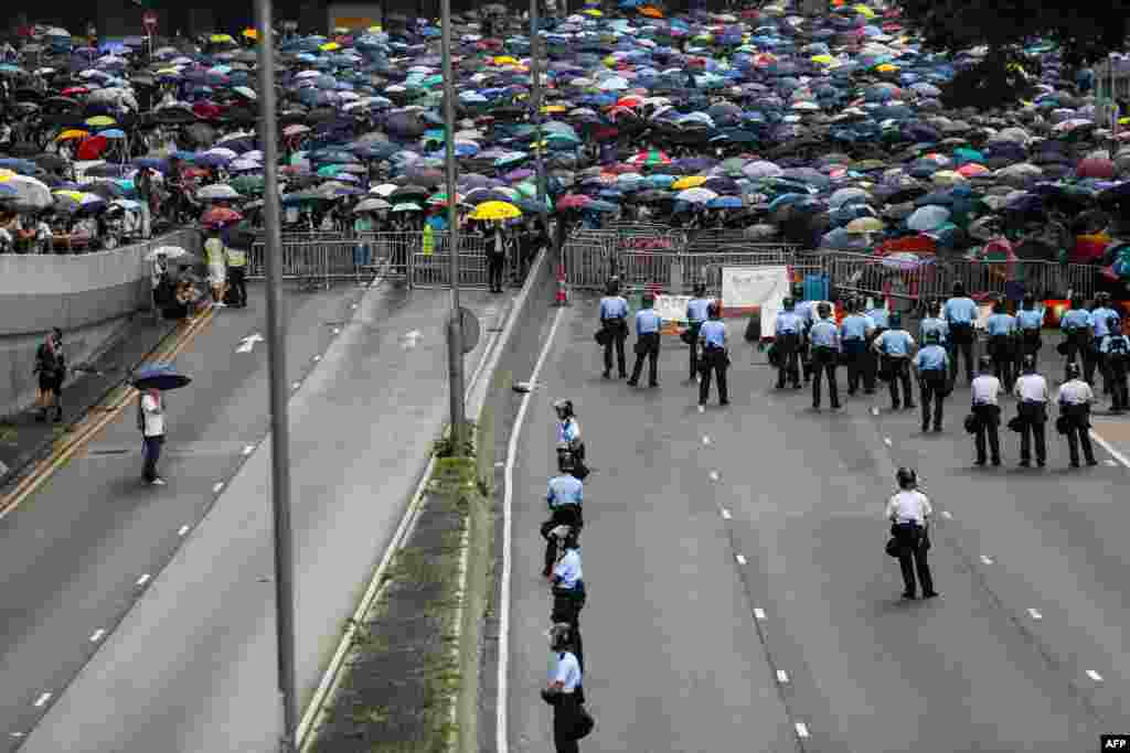 2019年6月12日香港抗议者在港府门外反对香港对中国的引渡法案,警察在道路上巡逻。数以万计的抗议者封锁了主要道路,致使香港中部地区瘫痪。上午稍晚时候,随着人群继续扩大,立法会官员表示,他们将把法案的二读“推迟到更晚的日期”。