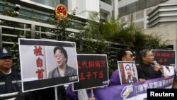香港民主抗议者举着铜锣湾书店老板桂民海(左)和李波(右)的肖像(2016年1月19日)。