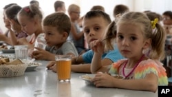 资料照:2022年7月8日,来自顿涅茨克地区孤儿院的孩子们在俄罗斯西南部罗斯托夫地区亚速海定居点的一个营地里吃饭。俄罗斯公开推进收养乌克兰儿童并将他们带回俄罗斯,这逐渐成为战争中最具爆炸性的问题之一。 (美联社照片)