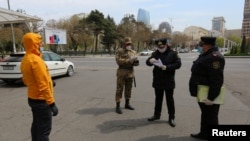 Azeri law enforcement officers and a serviceman check documents of a man after the authorities imposed restrictions on movement to prevent the spread of the coronavirus disease (COVID-19) in Baku, Azerbaijan, April 6, 2020.