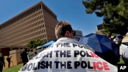 在2020年6月3日凤凰城的抗议活动中,抗议者身披要求取消当地警察局的横幅(美联社)。
