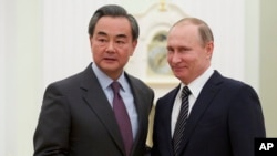 2016年3月11日,俄罗斯总统普京(右)在莫斯科与中国外长王毅握手。(资料照片)